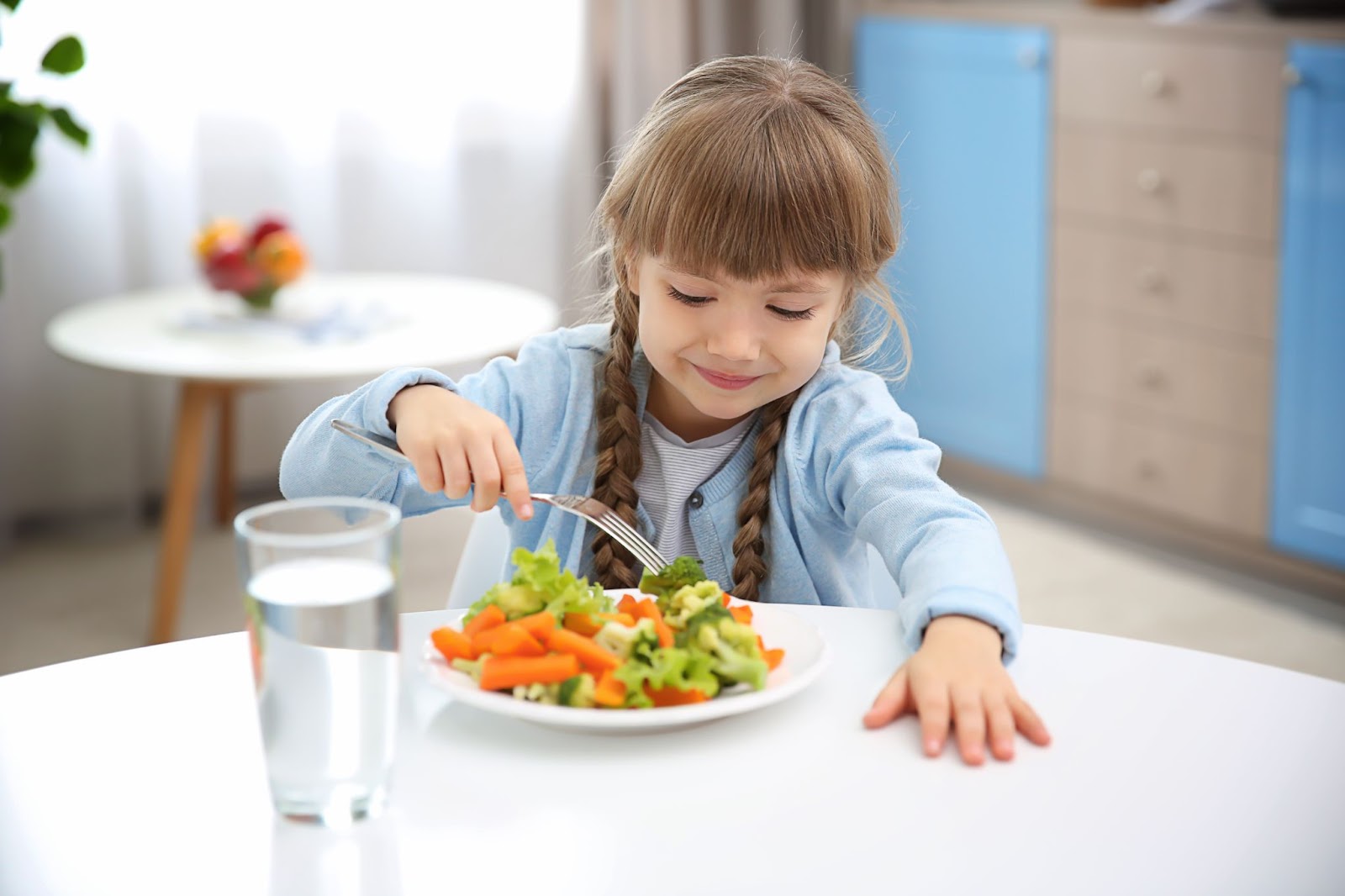 Fetiță mâncând legume în bucătărie
