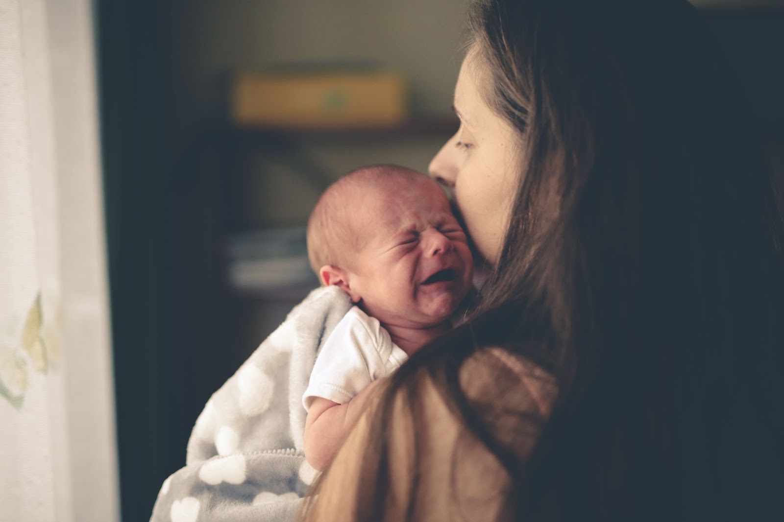 Nou-născut plânge în brațele mamei.