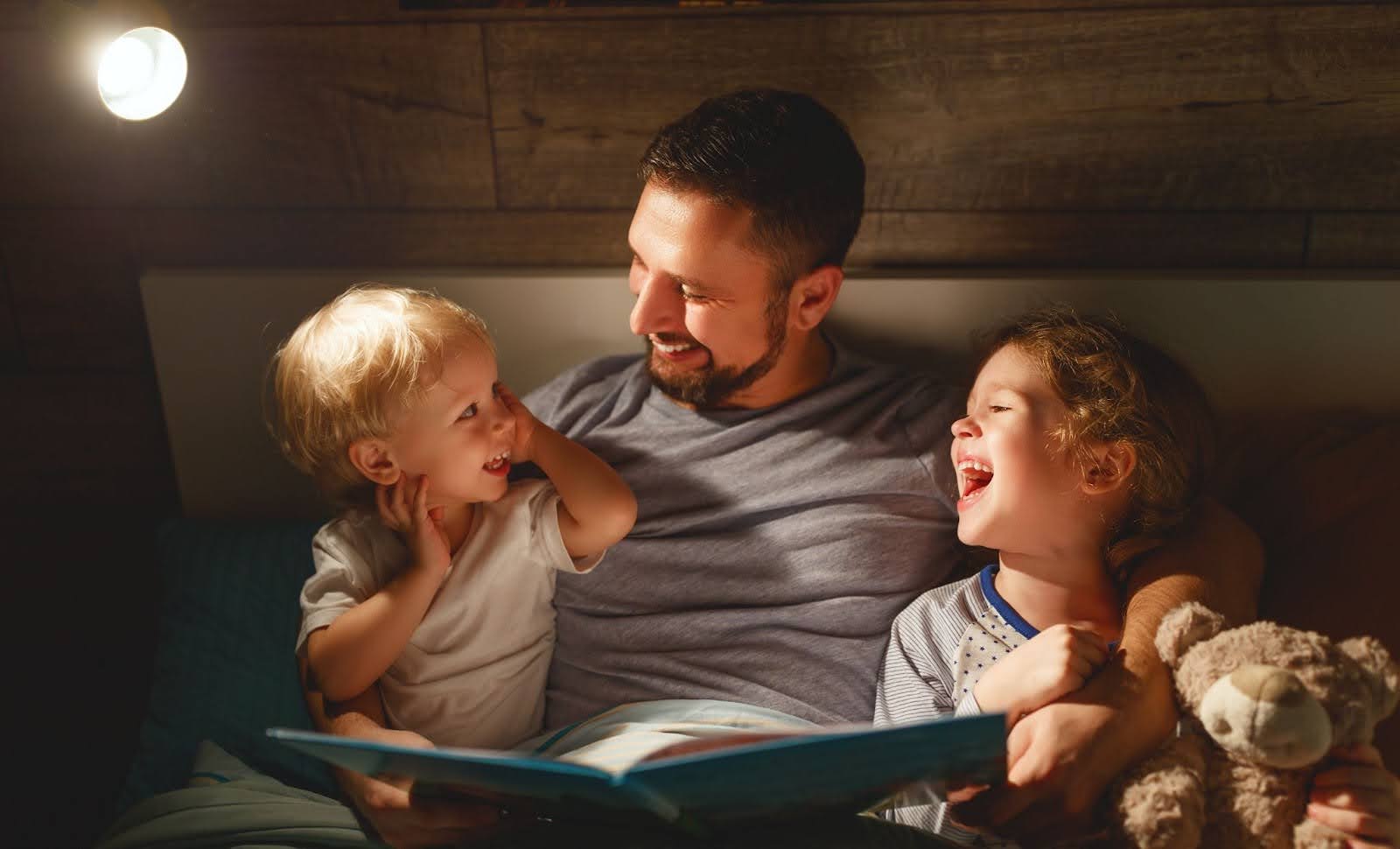 Tatăl citește copiilor povești înainte de culcare.